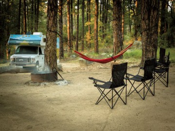 Camper met stoelen en hangmat in het bos