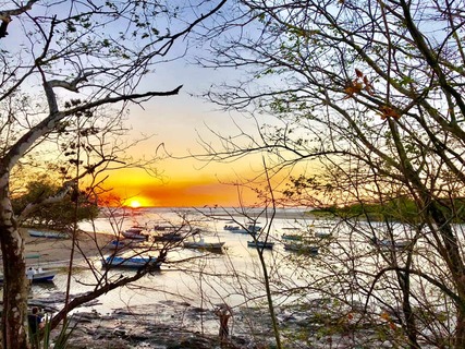 Prachtig uitzicht op de zonsondergang vanuit Tamarindo, in Costa Rica, met boten op het water en bomen