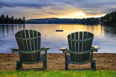 Twee houten stoelen op strand bij zonsondergang. Algonquin provinciaal park, Canada