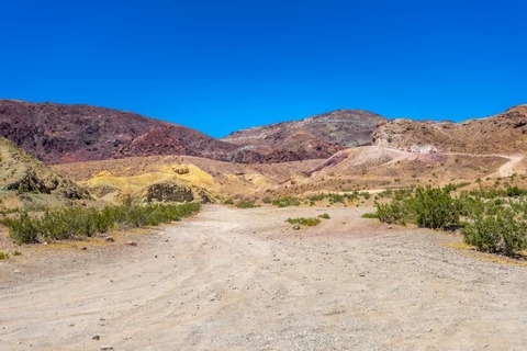 Een onverharde weg in het Odessa Canyon-gebied bij Yermo, Californië, in de Mojave-woestijn met kleurrijke bergen.