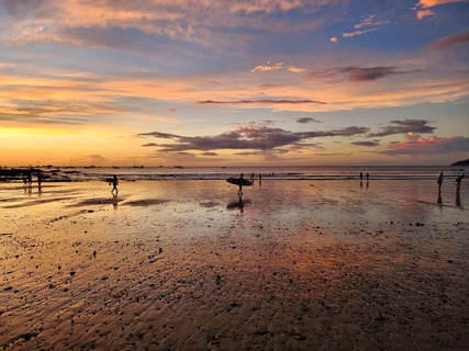 Panorama bij zonsondergang met surfers op het strand van Tamarindo in Tamarindo, Costa Rica
