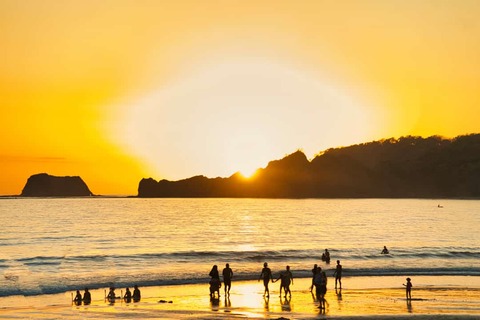 mensen in de zee met zonsondergang Samara Beach Costa Rica