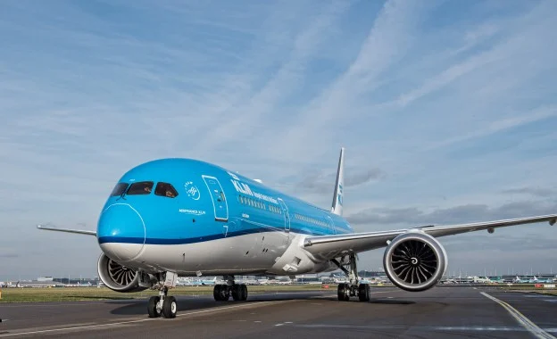 Blauw wit KLM vliegtuig taxiet over het platform van een luchthaven met de motoren op de voorgrond
