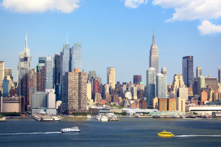 Skyline van Manhattan met het Empire State Building en wolkenkrabbers gezien vanaf de rivier met veerboten op het water