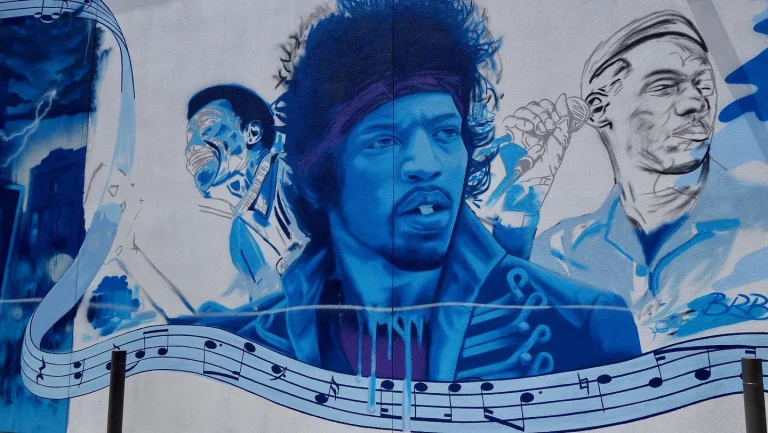 Grote blauwe muurschildering met portretten van Jimi Hendrix en andere muzikanten met een notenbalk op een gebouw in Dallas