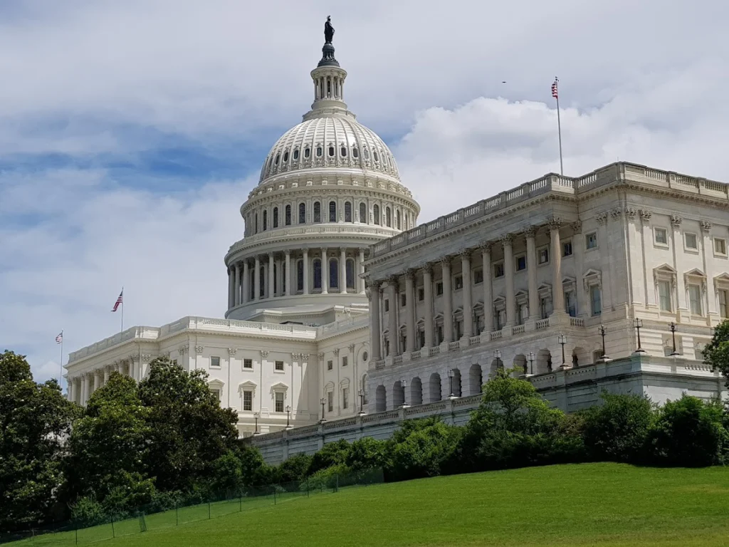 Het witte Capitool met zijn koepel en zuilengalerij in Washington D.C. omringd door groene bomen en een gazon