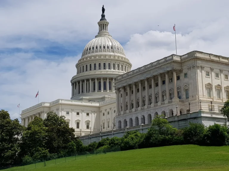Het witte Capitool met zijn koepel en zuilengalerij in Washington D.C. omringd door groene bomen en een gazon