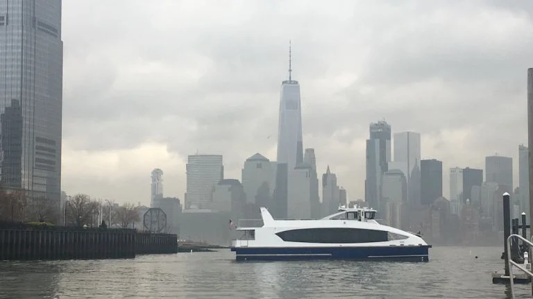 Witte veerboot vaart voor de skyline van Lower Manhattan met de hoge spits van One World Trade Center in de mist