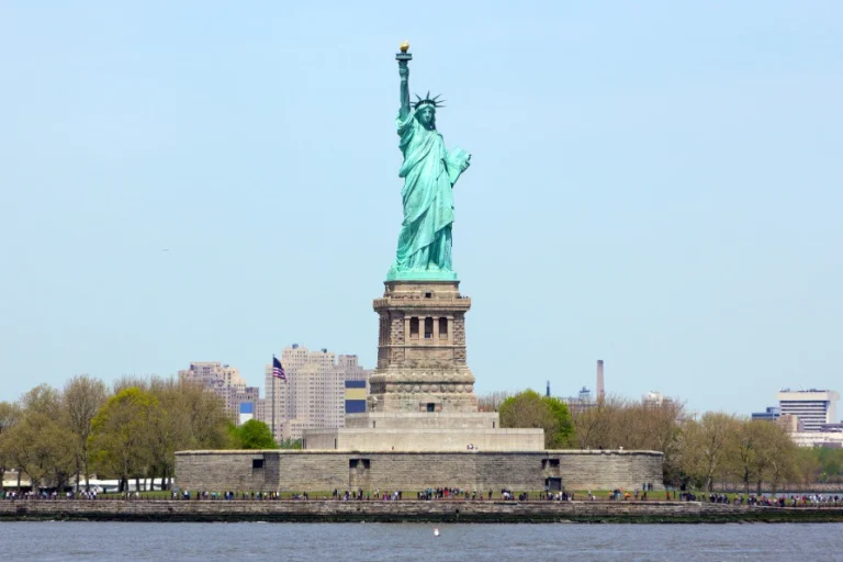 Het groene Vrijheidsbeeld op zijn sokkel op Liberty Island met de skyline van New York op de achtergrond
