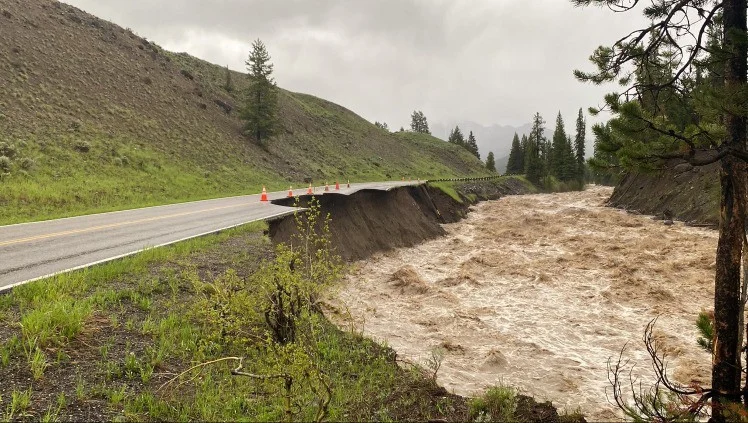 Sterk gezwollen rivier heeft een deel van de weg met kegels afgezet weggeslagen in Yellowstone National Park