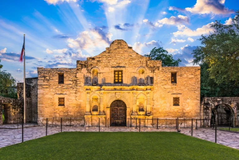De historische gevel van The Alamo verlicht door de laatste zonnestralen met een stralenkrans van wolken erboven in San Antonio