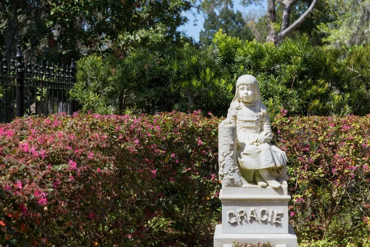 Wit marmeren standbeeld van een zittend meisje tussen bloeiende struiken op Bonaventure Cemetery in Savannah
