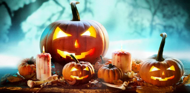Groep uitgesneden Halloween pompoenen met enge gezichten tussen brandende kaarsen op een houten ondergrond in een mistige blauwe sfeer