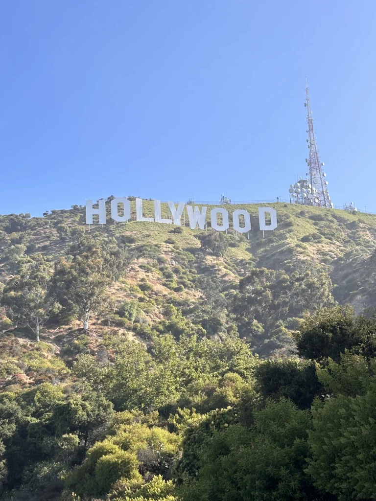 Witte letters van het Hollywood bord op een groene heuvel met een zendmast ernaast onder een strakblauwe hemel