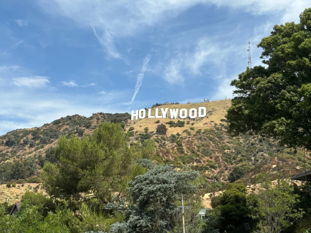 Witte letters van het Hollywood bord op de beboste heuvel bij Los Angeles onder een lichtbewolkte hemel