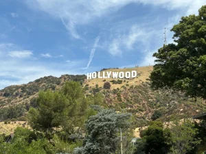 Witte letters van het Hollywood bord op de beboste heuvel bij Los Angeles onder een lichtbewolkte hemel