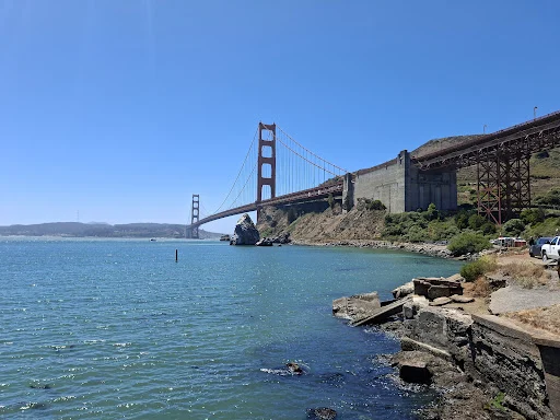 De oranjerode Golden Gate Bridge overspant de baai van San Francisco gezien vanaf een rotsachtige oever