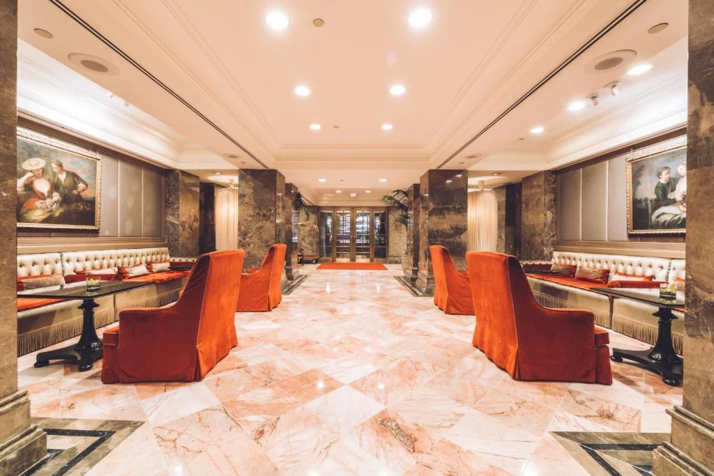 Sfeervolle marmeren lobby met fluwelen fauteuils en schilderijen in The Michelangelo Hotel, een deluxe hotel in Midtown Manhattan