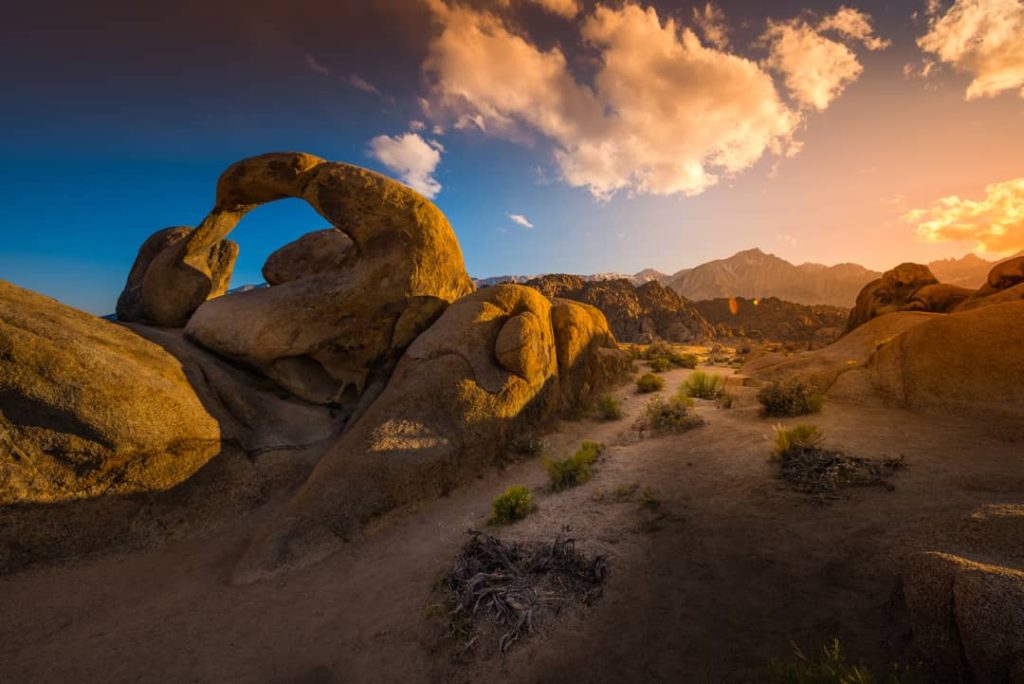 Natuurlijke rotsboog van gestapelde granietrotsen tegen een oranje gloeiende avondlucht in de Alabama Hills