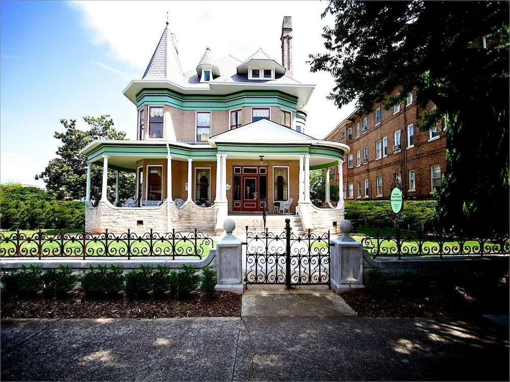 Statig victoriaans herenhuis met torentjes en een brede overdekte veranda achter een smeedijzeren hek in Birmingham, Alabama