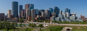Panorama van de moderne skyline van Calgary in Alberta met wolkenkrabbers, een rivier en een witte boogbrug op een zonnige dag