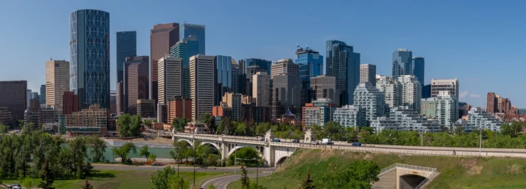 Panorama van de moderne skyline van Calgary in Alberta met wolkenkrabbers, een rivier en een witte boogbrug op een zonnige dag