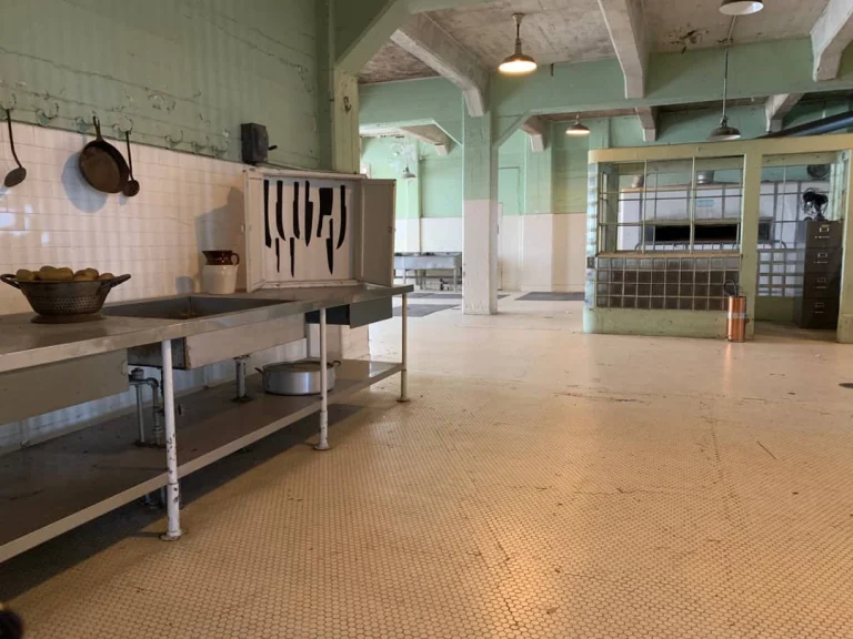 Verlaten gevangeniskeuken op Alcatraz Island met een roestvrijstalen aanrecht, een kast met omtrekken van messen en een tegelvloer
