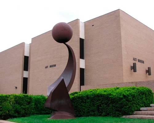Bakstenen museumgebouw met de tekst Art Museum en een abstract bronzen beeldhouwwerk van een bol op een gebogen voet ervoor in Amarillo