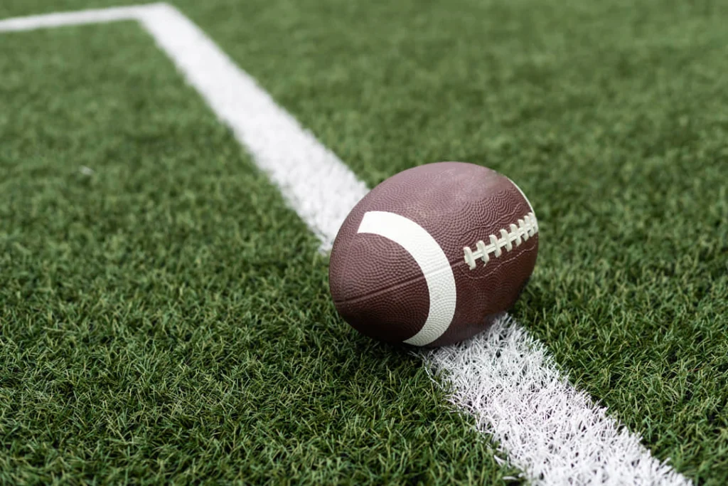Bruine American football met witte veters ligt op de wittelijn van een groen grasveld