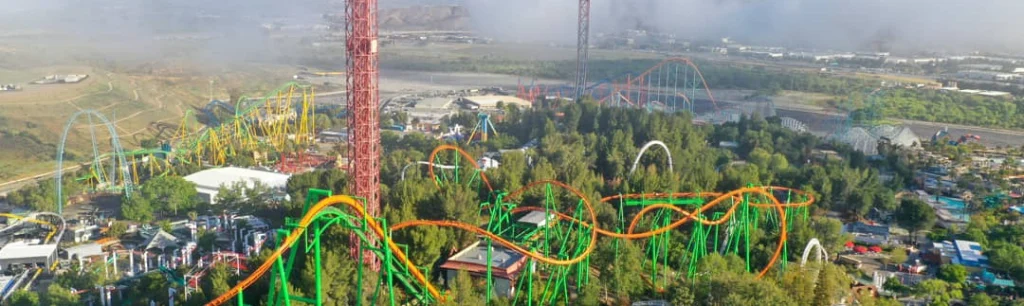 Luchtfoto van een pretpark in Amerika met felgekleurde achtbanen tussen groene bomen en attractietorens