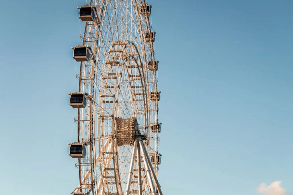 Groot reuzenrad met lege gondels steekt af tegen een heldere blauwe lucht in een pretpark