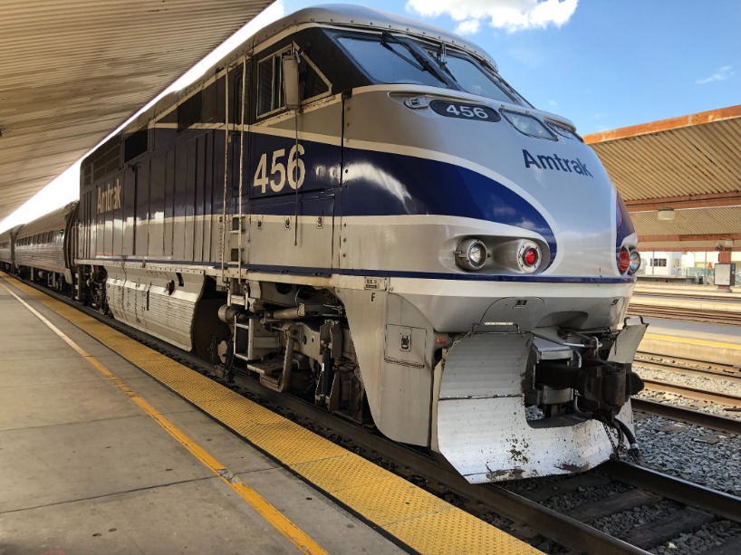 Neus van een blauw witte Amtrak locomotief geparkeerd langs een overdekt treinperron