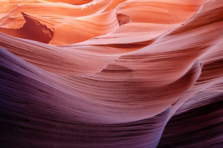 Gladde, golvende zandsteenwanden in warme rood- en paarstinten in de Antelope Canyon