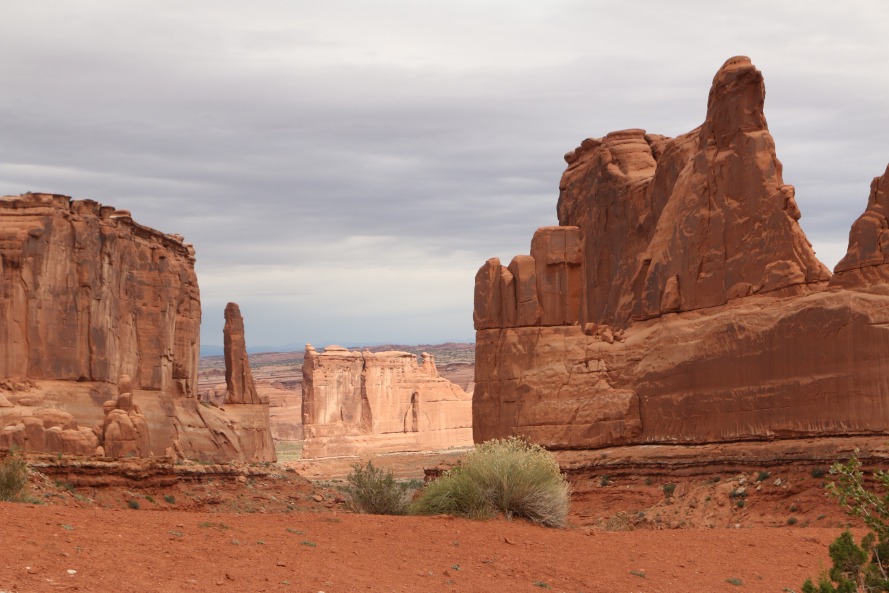 Verticale rode rotstorens rijzen op langs het wandelpad Park Avenue onder een bewolkte lucht in Arches National Park