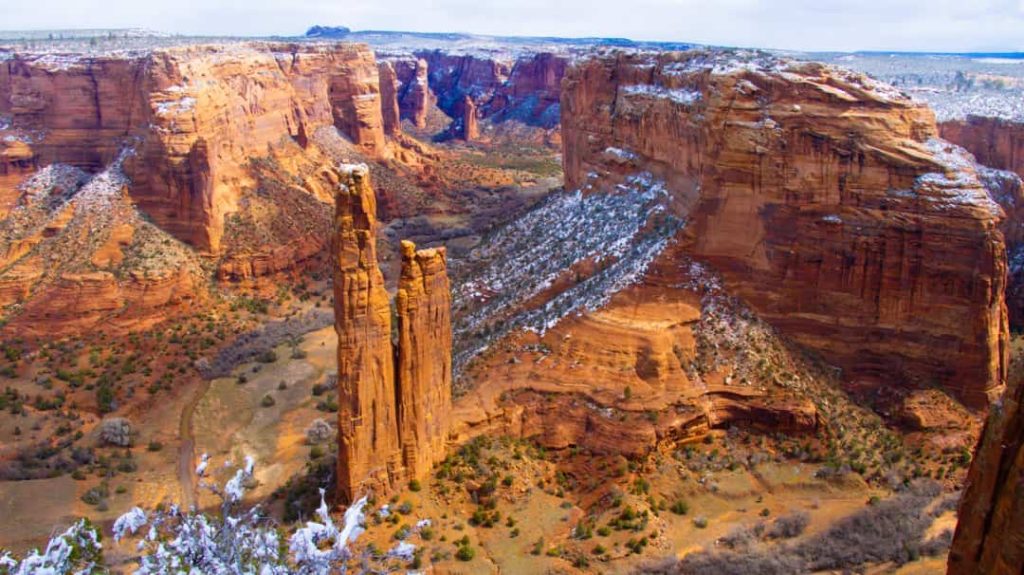 Hoge slanke rotspilaar genaamd Spider Rock omringd door besneeuwde canyonwanden in Canyon de Chelly in Arizona
