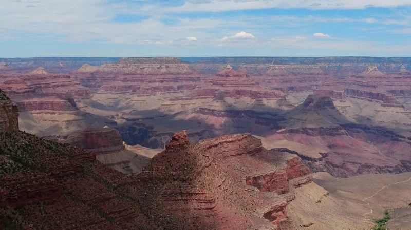 Wijds uitzicht over de roodbruine, gelaagde rotswanden en pieken van de Grand Canyon vanaf de zuidrand