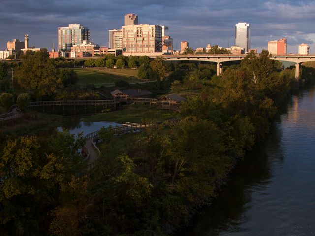Uitzicht op de skyline van Little Rock in Arkansas met wandelpaden, groene parken en een brug over de rivier bij zonsondergang
