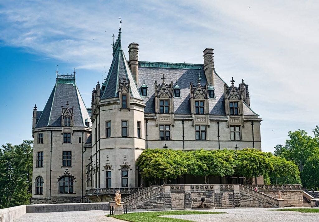Imposante voorgevel van het kasteelachtige landhuis Biltmore Estate met puntdaken, torens en schoorstenen tegen een blauwe lucht