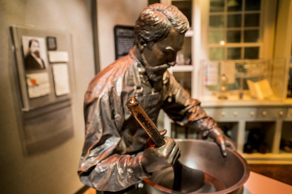 Bronzen standbeeld van een man die met een lepel roert in een grote pan, uitbeelding van apotheker John Pemberton in het World of Coca-Cola museum in Atlanta