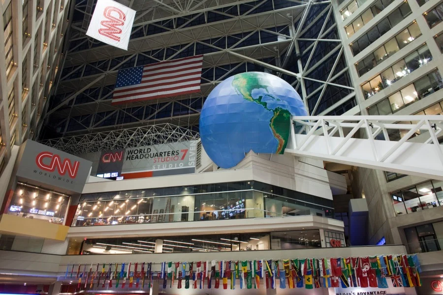 Grote hangende wereldbol en Amerikaanse vlag in het atrium van het CNN World Headquarters in Atlanta, omringd door vlaggen van verschillende landen