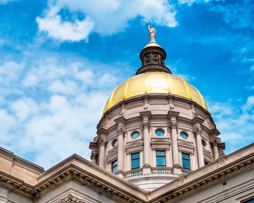 Close-up van de gouden koepel met standbeeld bovenop het Georgia State Capitol tegen een blauwe lucht met wolken in Atlanta