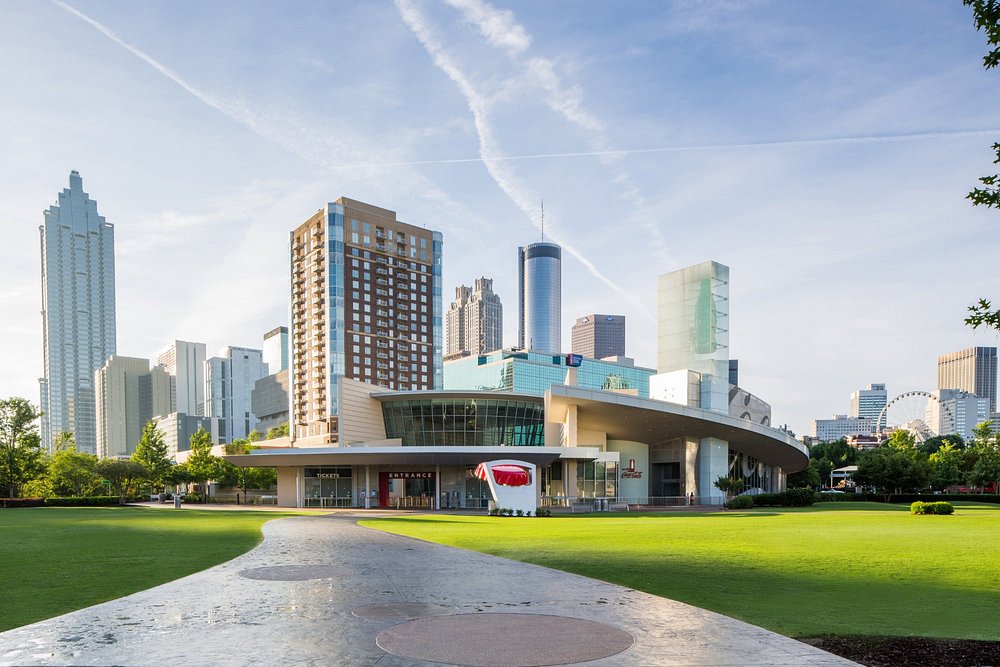 Modern museumgebouw van het World of Coca-Cola met een groen grasveld ervoor en de skyline van Atlanta op de achtergrond