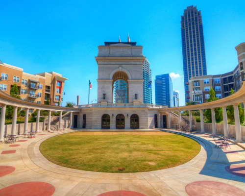 Grote stenen triomfboog met zuilen omringd door een colonnade en wolkenkrabbers op Atlantic Station in Atlanta onder een strakblauwe lucht