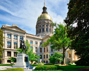 Wit gebouw met gouden koepel van het Georgia State Capitol in Atlanta, met een ruiterstandbeeld op een sokkel ervoor