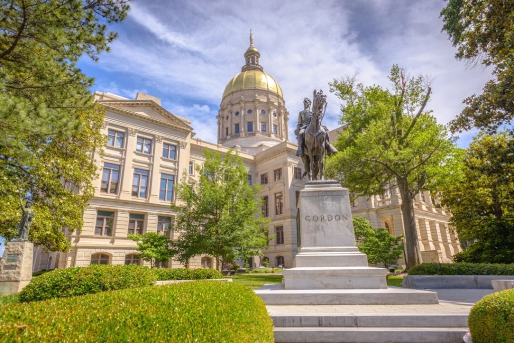 Gouden koepel van het Georgia State Capitol in Atlanta gezien tussen bomen door, met een ruiterstandbeeld op de voorgrond
