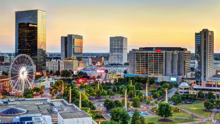 Uitzicht over de skyline van Atlanta bij zonsondergang met wolkenkrabbers, een reuzenrad en het groene Centennial Olympic Park op de voorgrond