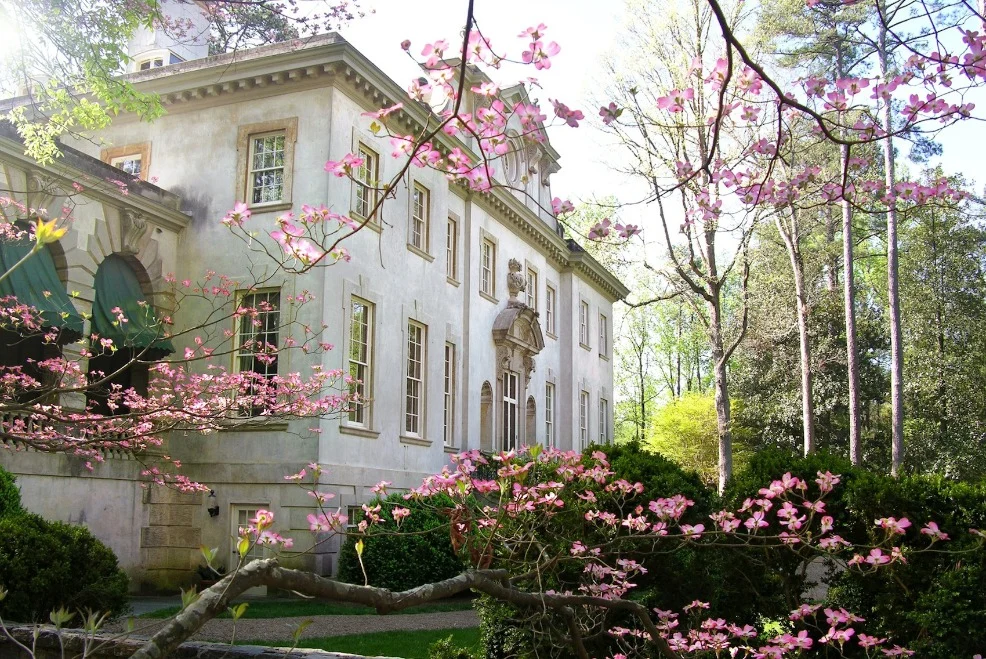 Het klassieke Swan House in Atlanta gezien tussen bloeiende roze sierkersen en groene tuinstruiken in het voorjaar