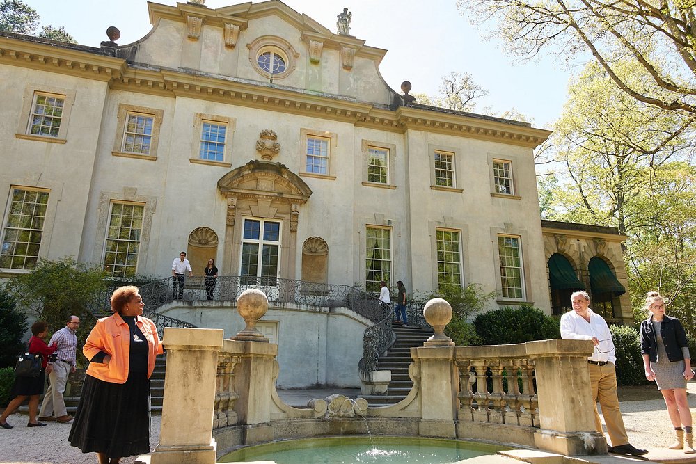 Gidsen en bezoekers staan op het terras van het statige landhuis Swan House bij een fontein onderaan de trap