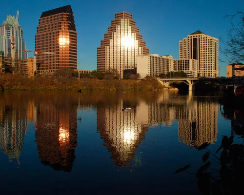 Wolkenkrabbers van Austin gloeiend in het avondlicht en weerspiegeld in het kalme water van Lady Bird Lake