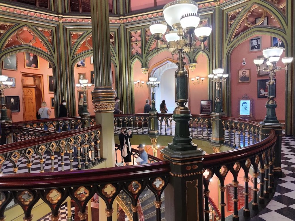 Bezoekers lopen over een balustrade in de kleurrijke, neogotische hal van de Old State Capitol in Baton Rouge met portretten aan de muur